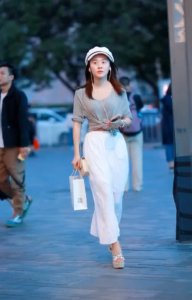白色檐帽享受音乐的姑娘 戴着耳机走在路上 引人注目