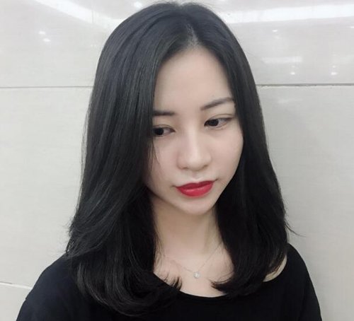 脸型有点长,厚厚的黑色中长发做成内扣直发发型,发尾在锁骨位置往外